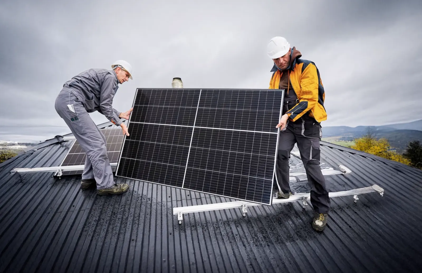 Two solar technicians installing a solar panel on a home roof